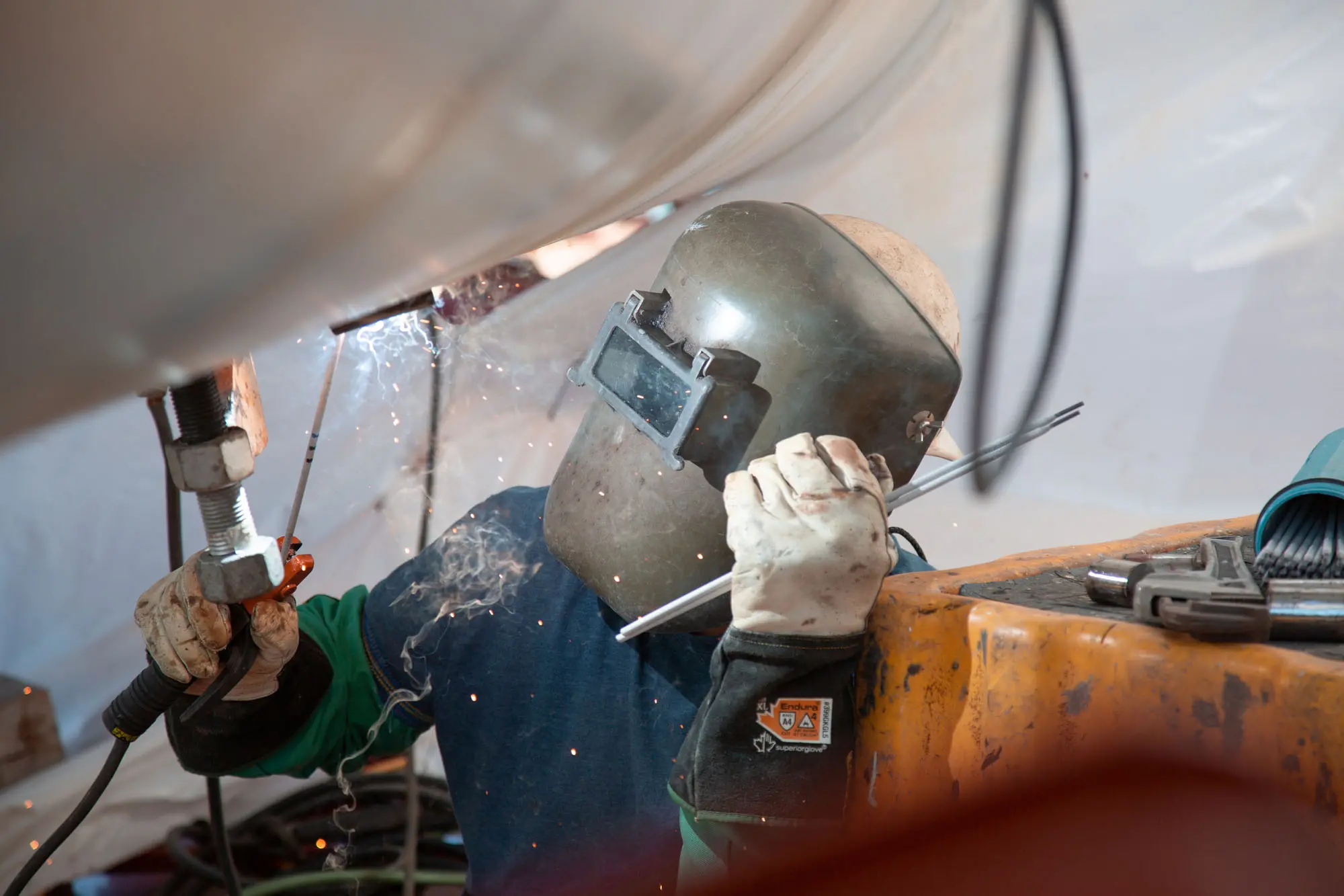 A welder craft professional welding a pipe on site.