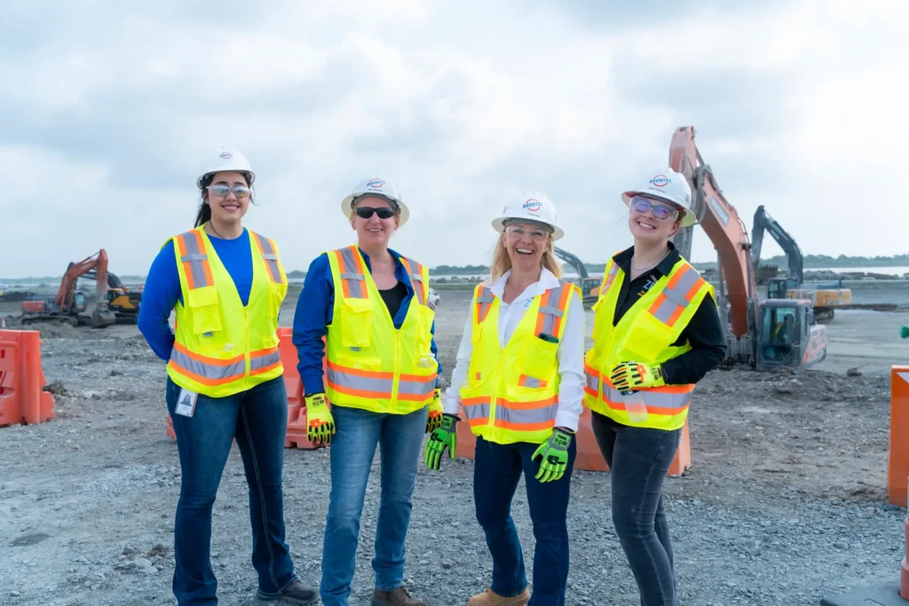 Project staff pose in front of excavators at the project site.