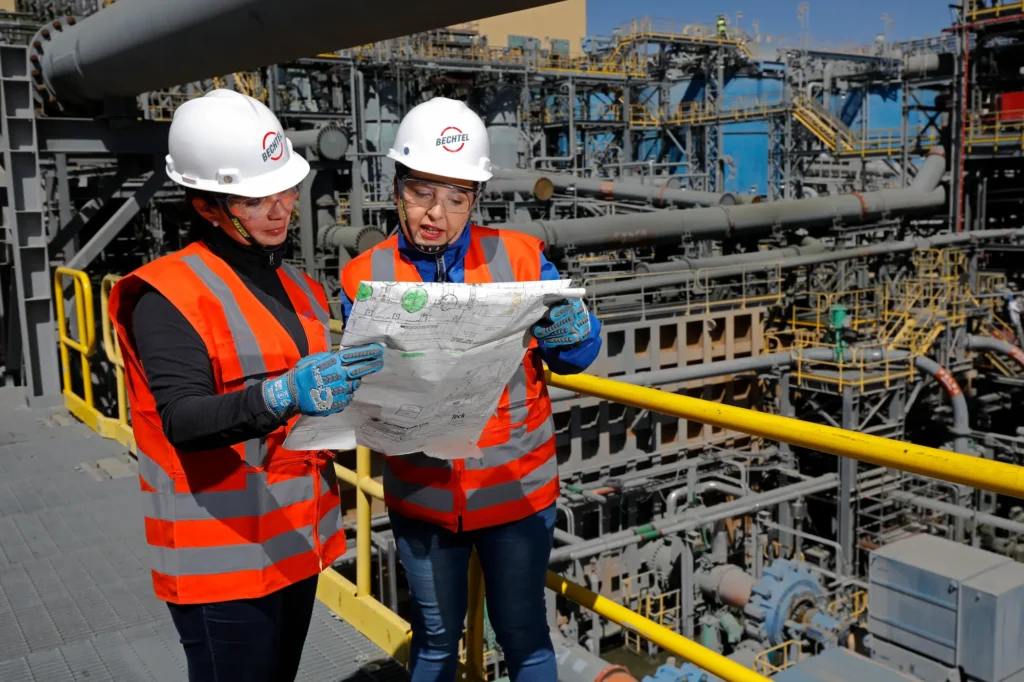 Two workers review plans at the QB2 job site.